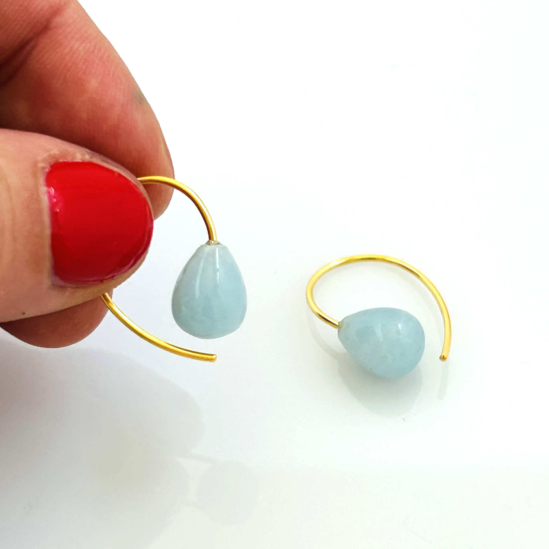 Detailansicht eines Aquamarin-Ohrhängers in Tropfenform, Bügel in glänzendem Gold